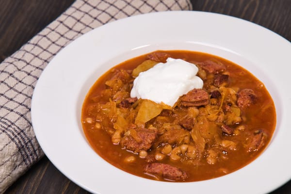 Kolbászos-babos savanyúkáposztás egytálétel paradicsomosan, tejföllel tálalva 